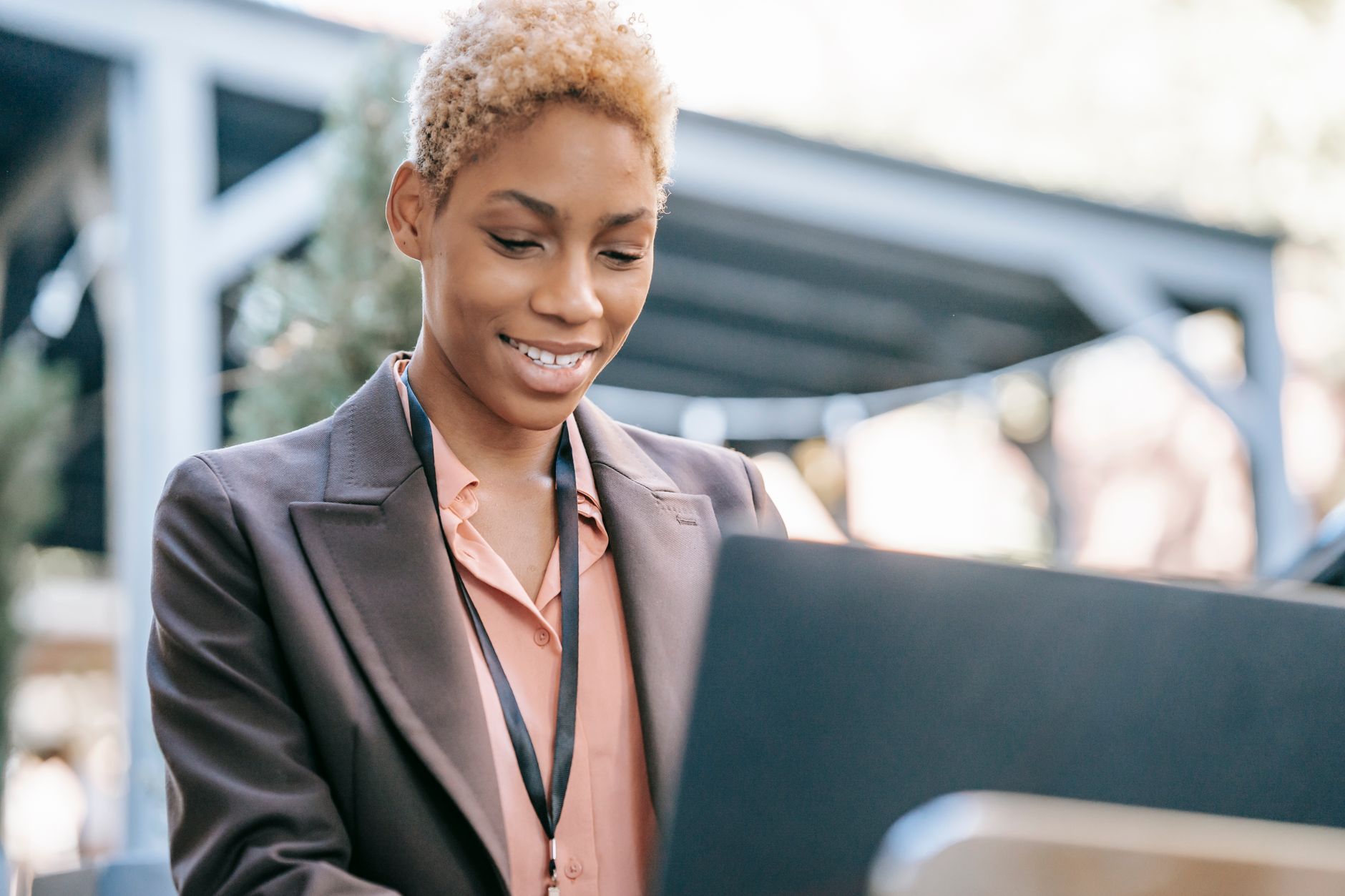 Low angle of positive African American businesswoman in formal wear browsing netbook while working outdoors