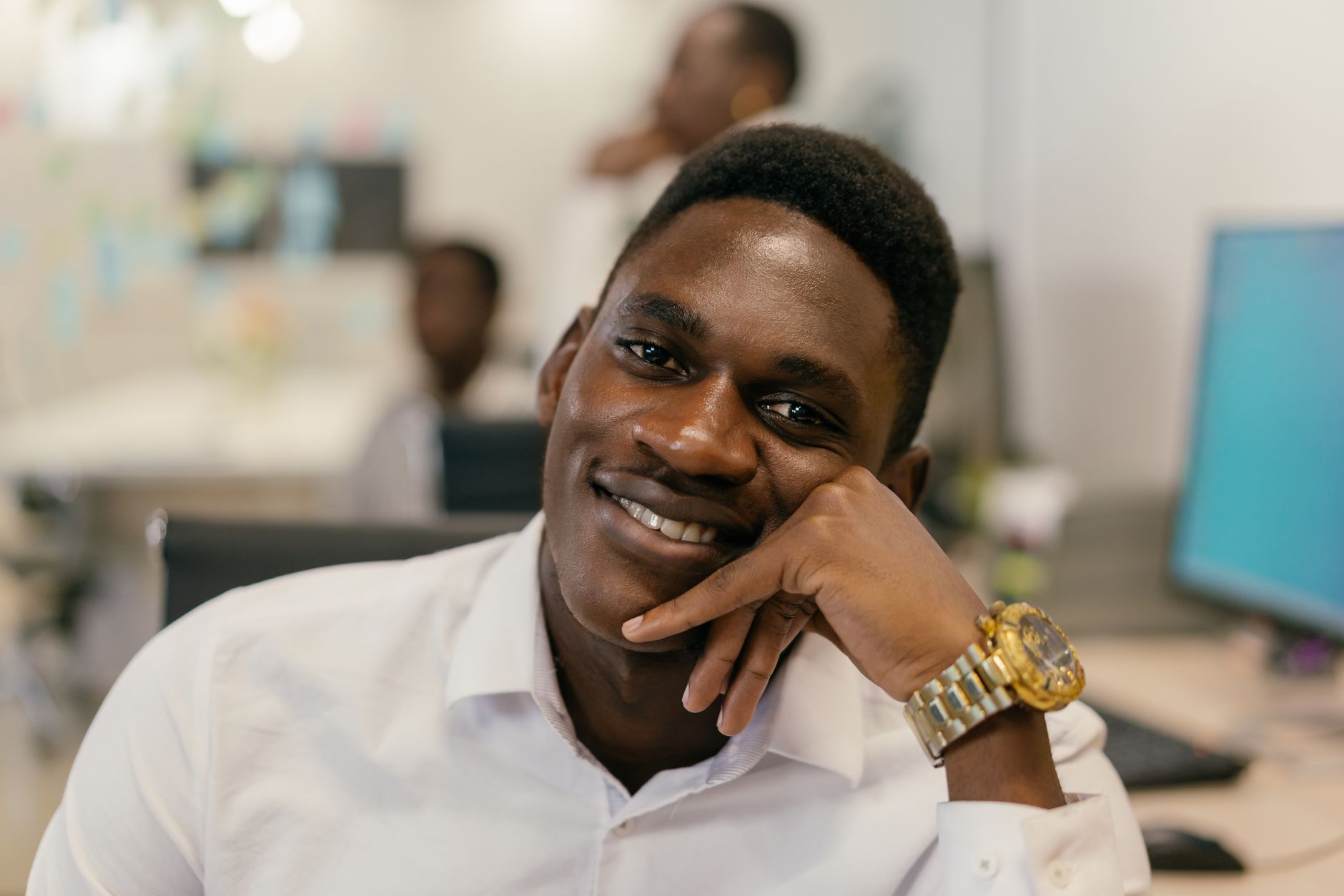 Close-up of a smiling man in a white shirt, relaxed in an office environment.